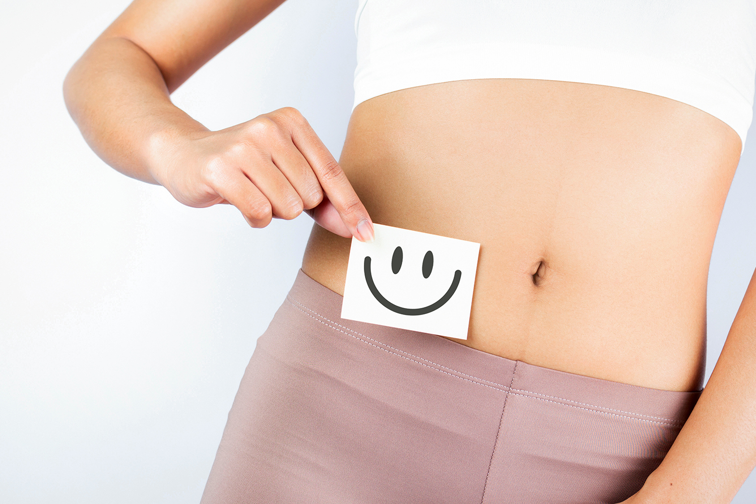 a woman holding a smiley face over her abdomen