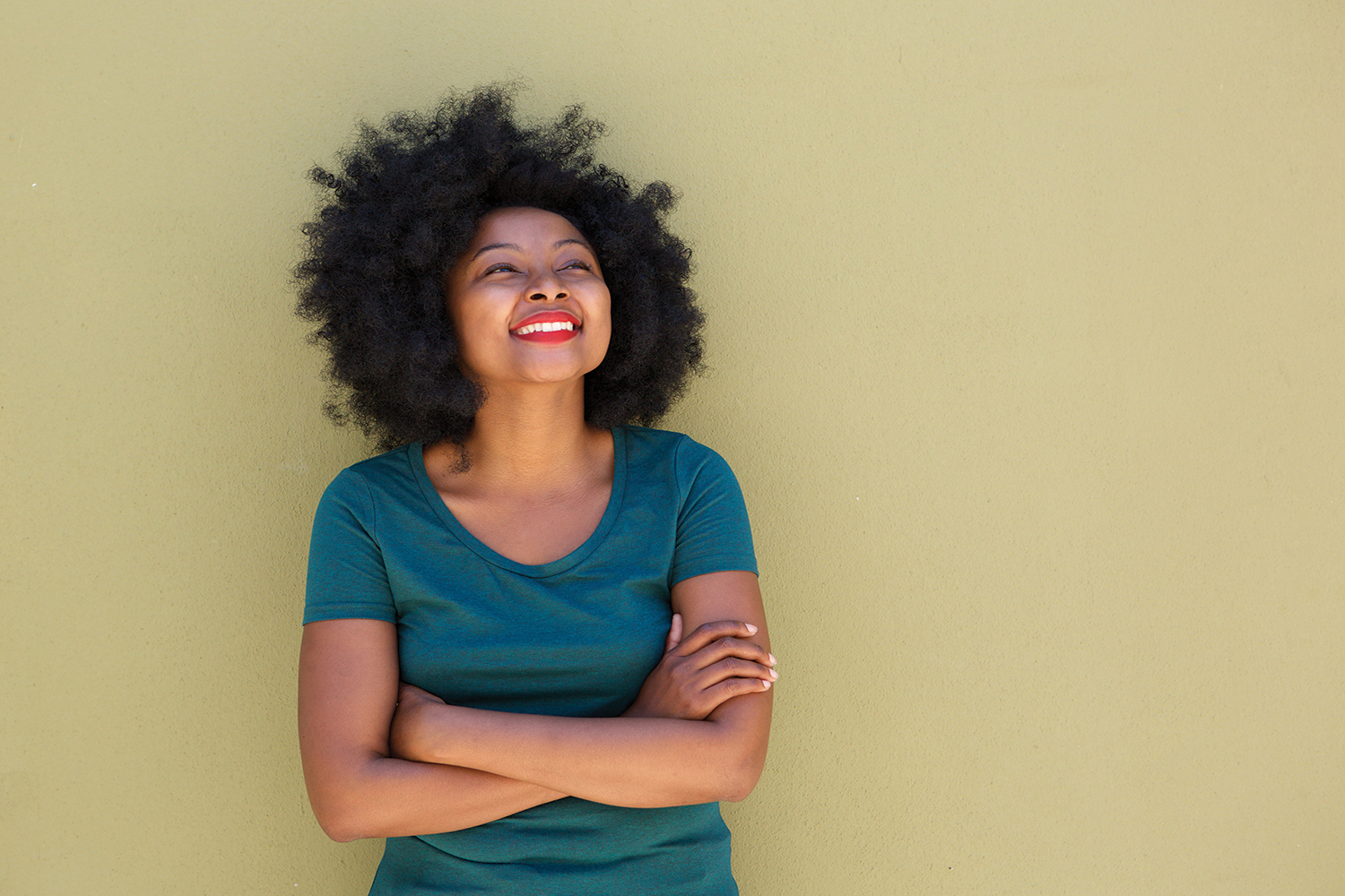 Happy woman with arms crossed looking upwards smiling