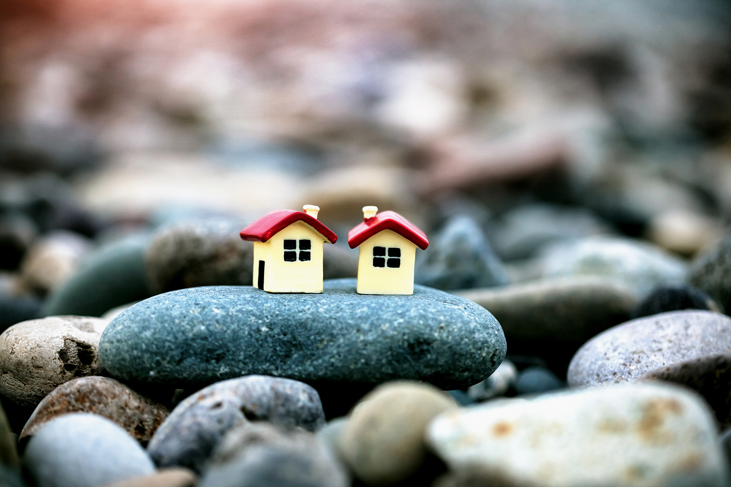 two small model houses sharing a pebble by the sea