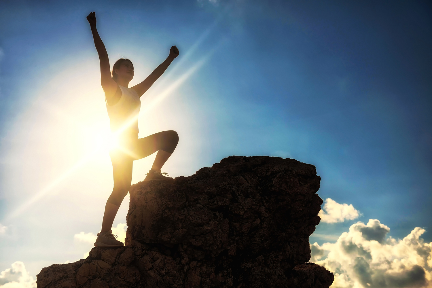a woman climbing to the summit on a sunny day