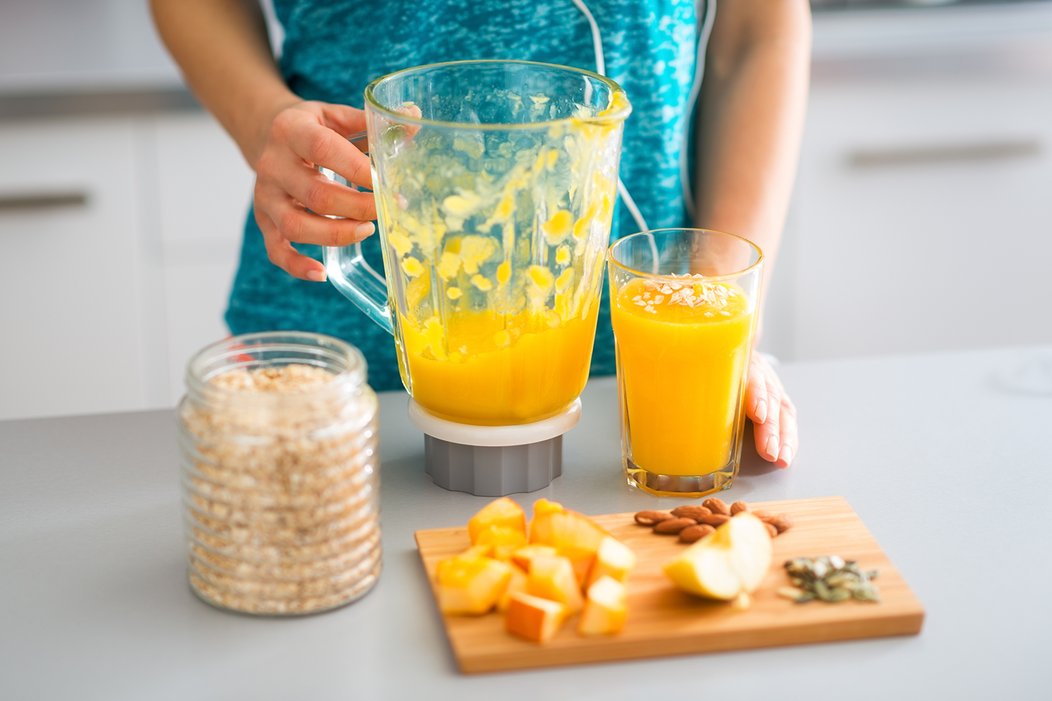 A woman making a protein smoothie with fresh fruits, nuts, and seeds