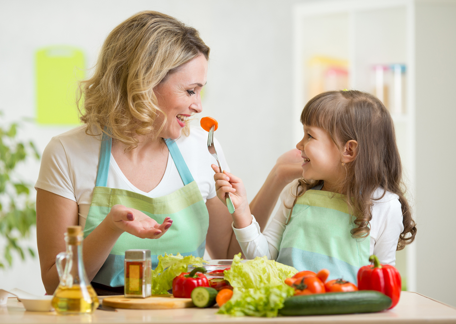 Child feeding mother vegetables.