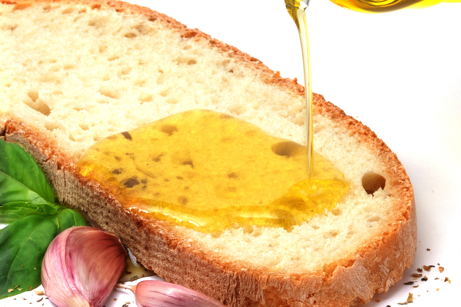 garlic cloves and oil being poured onto bread