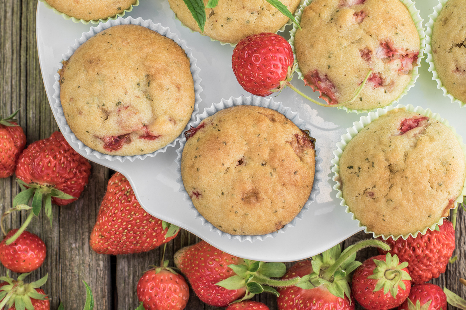 Top view on a strawberry muffins on white plate on a old wooden board
