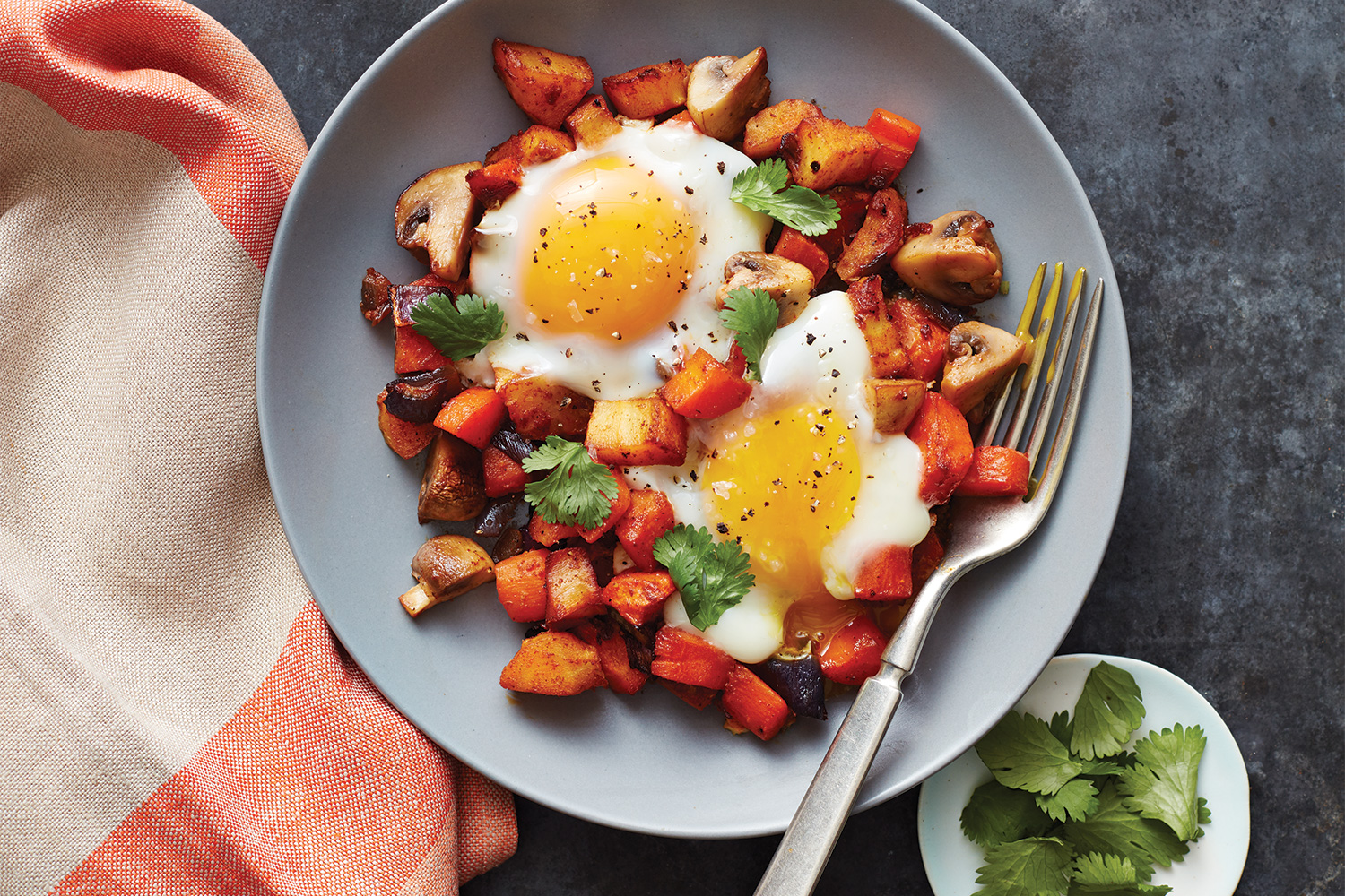 A bowl of vegetable hash with eggs roasted on top