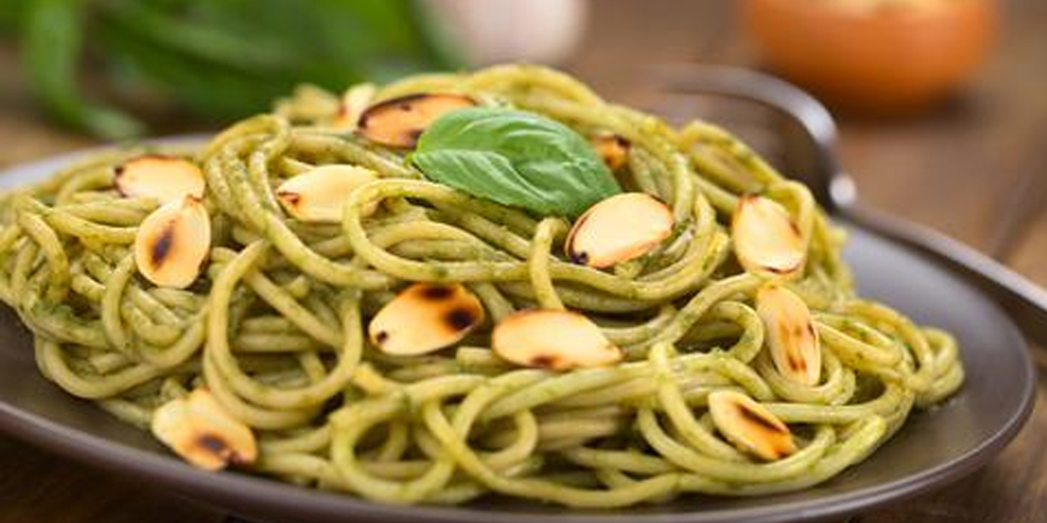 Dish of whole grain pasta, pesto and slivered almonds.