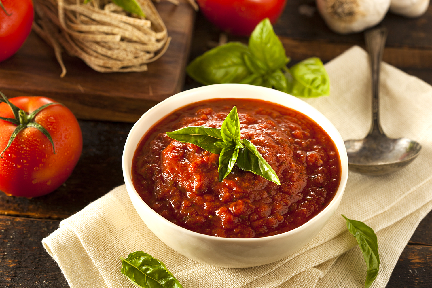 a bowl of marinara with a basil garnish
