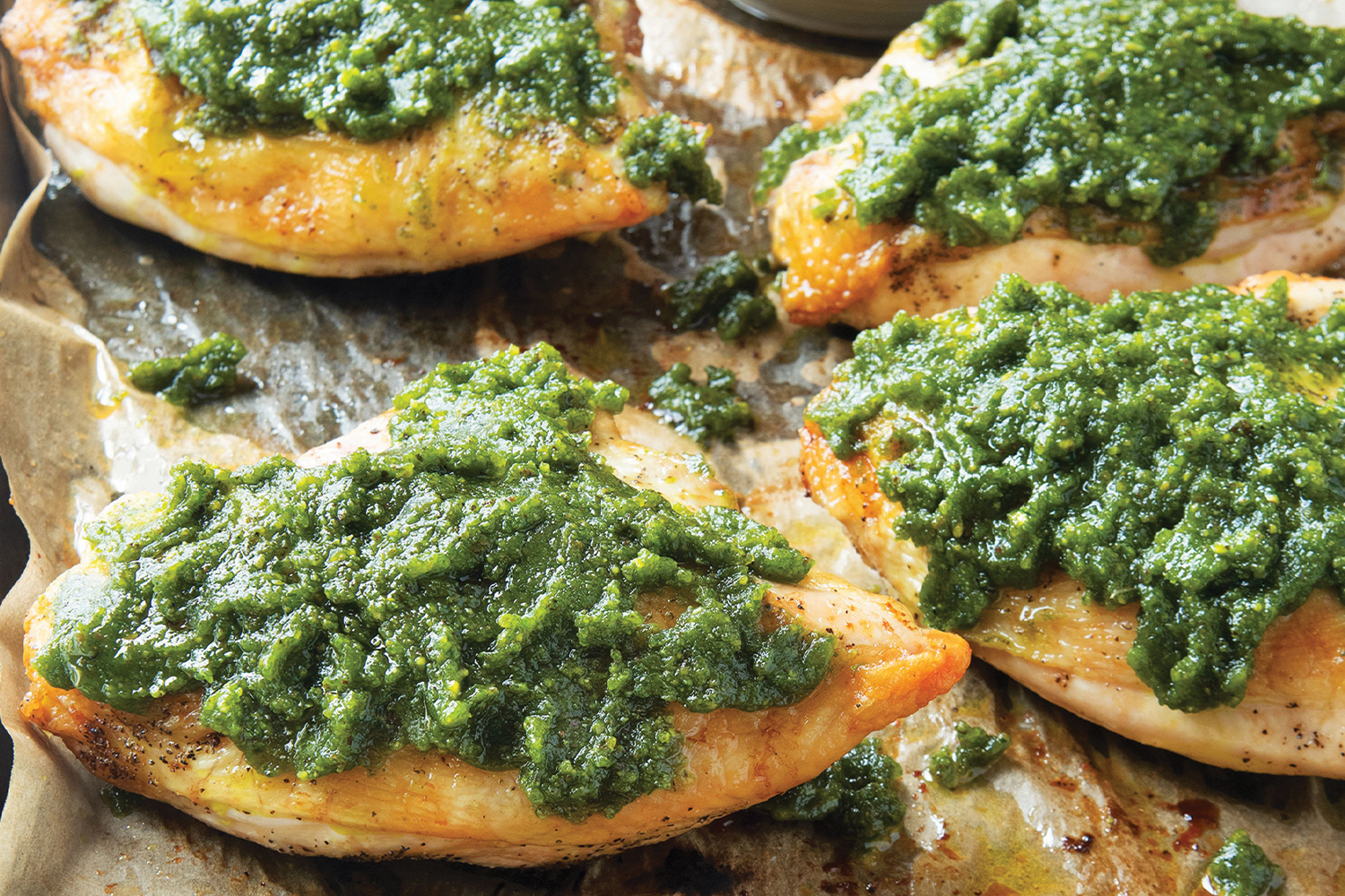 Pistachio Pesto Chicken on a baking sheet with parchment paper.