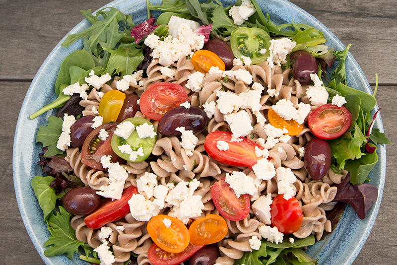 A bowl of pasta salad topped with vegan tofu feta