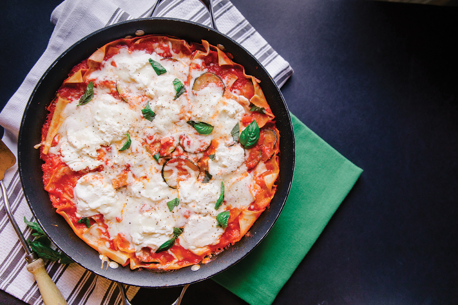 Top view of Veggie Skillet Lasagna, ready to serve from skillet, on a black background.