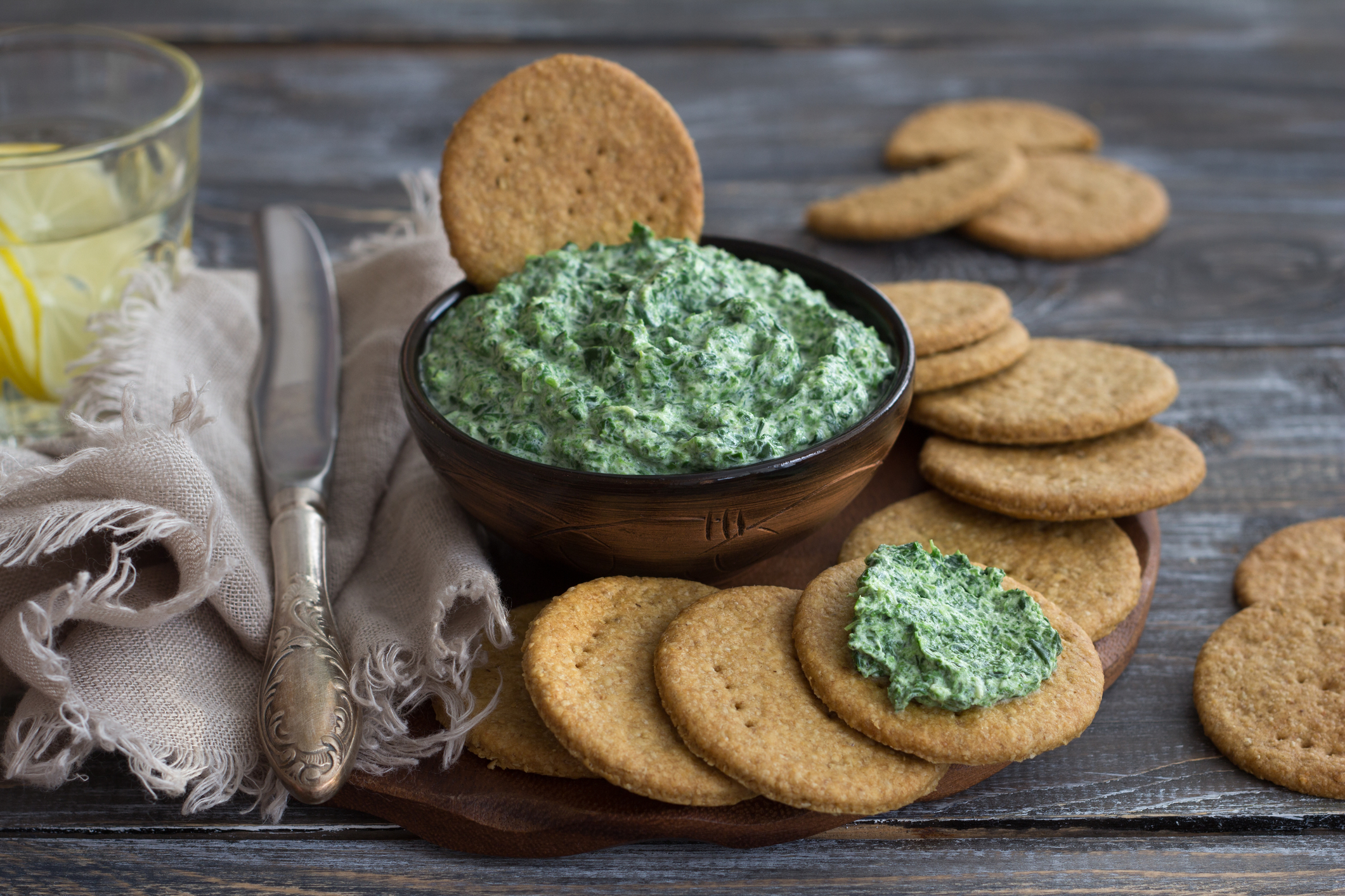 Vegan green spinach dip with on a wooden board with oat crackers,