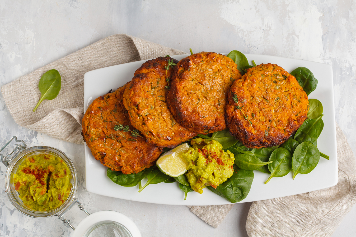 Sweet Potato and Mustard Turkey Burgers on a white platter on a bed of spinach greens.