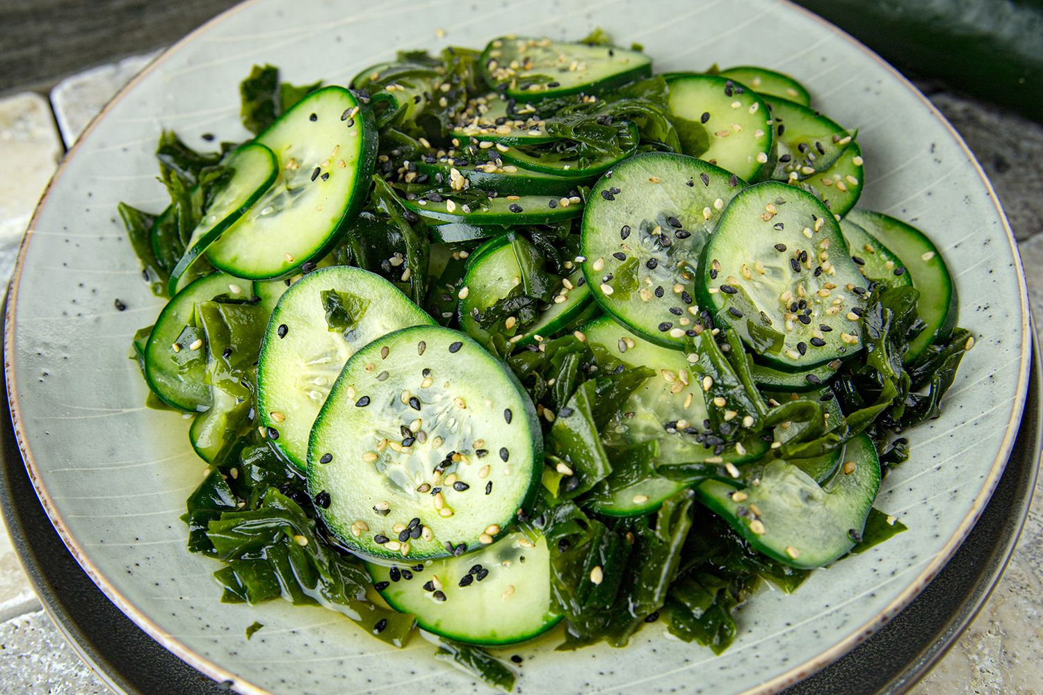 a plate of cucumber with oil, vinegar, wakame flakes, and sesame