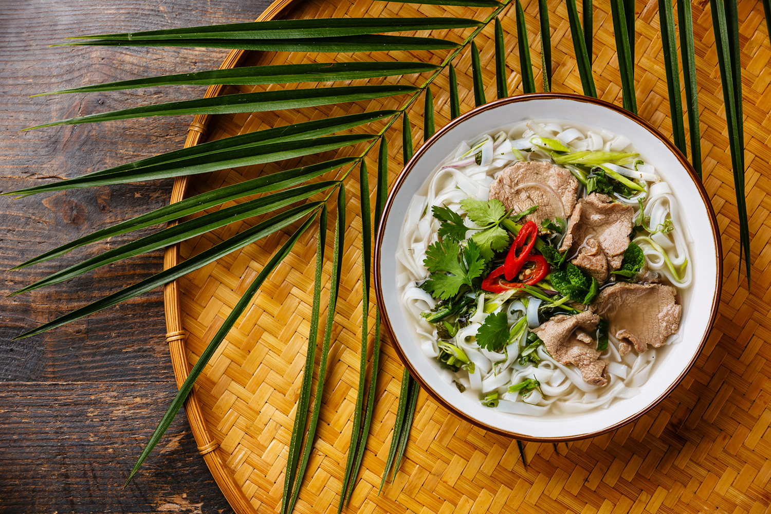 Pho Bo vietnamese Soup with beef on bamboo tray on wooden background.