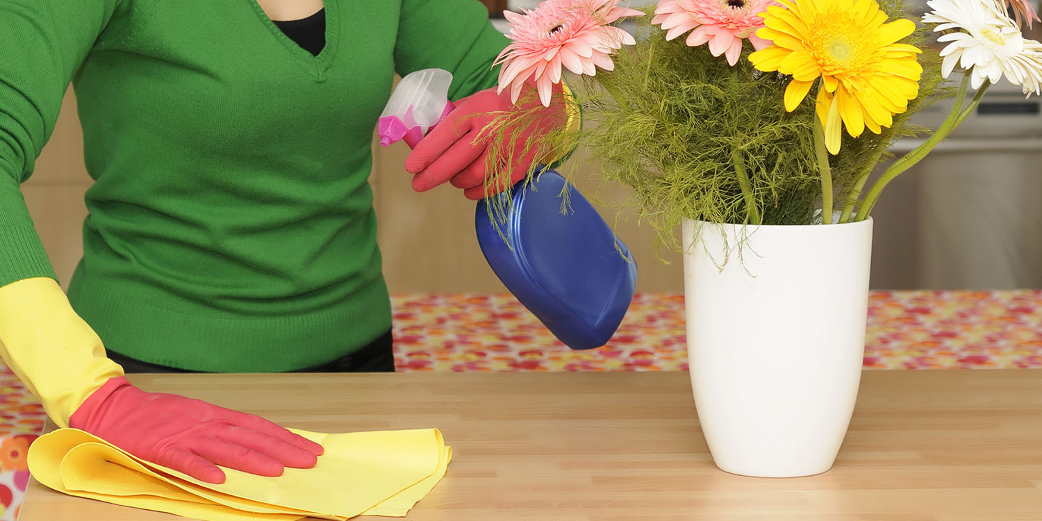 a woman wiping down a table with all-natural cleaning supplies