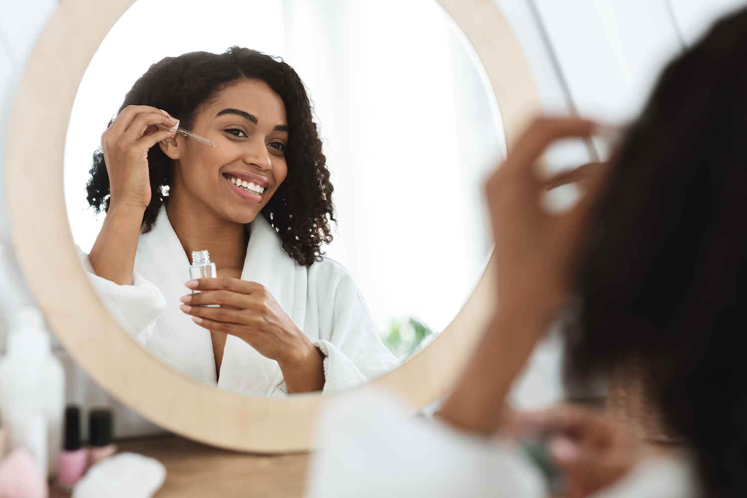 a woman applying oils to her face in the mirror