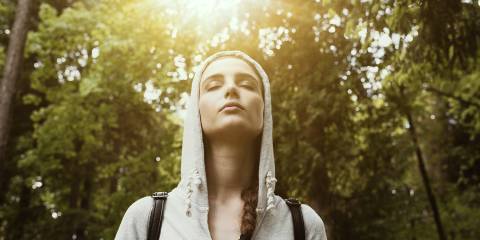 a young woman stopping to take a peaceful moment to breathe deeply