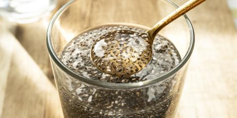 a glass of chia seeds in water, soaking into a gel that collects on a spoon