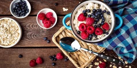 Oatmeal, oats and berries on a rustic wooden table.