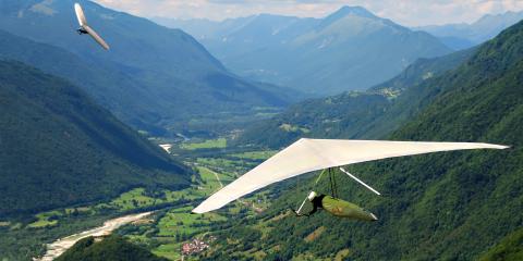 Person hang gliding through mountains. 