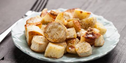 Roasted parsnips on a blue china plate on a dark wooden background.