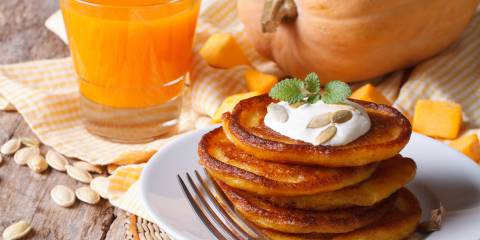 a stack of pumpkin pancakes and a glass of orange juice