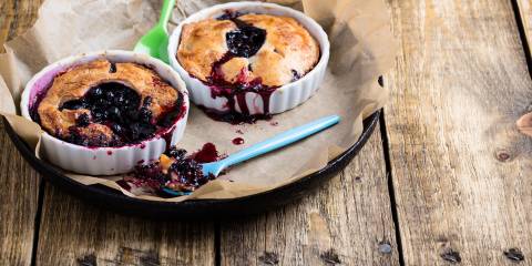 Individual blueberry pies on a rustic wooden table.