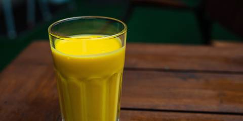 a tall glass of a creamy mango smoothie