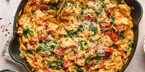 a pan of seasoned chicken with orzo and spinach