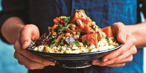 A man holding a heaping plate of Veggie Tagine