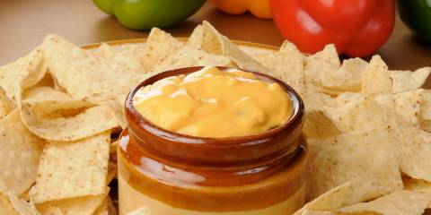 A dip with veggies surrounded by tortilla chips