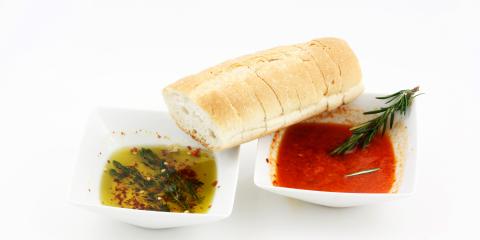 Crusty bread with two types of dipping bowls, one filled with golden oil, the other with a red oil.