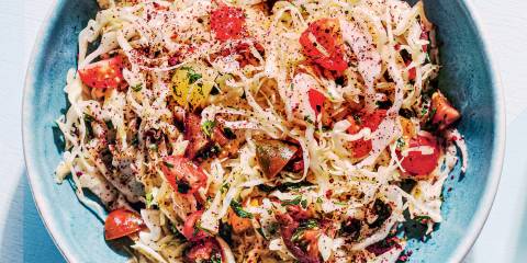 a bowl of cabbage, cherry tomatoes, parsley, and spices