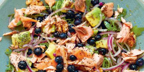 a plate with smoked salmon, blueberries, nuts, and greens