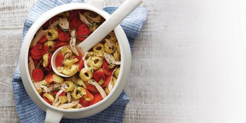 Chicken tortellini soup in a white soup crock.