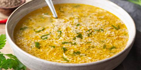 a bowl with broth, a dropped egg, and cilantro