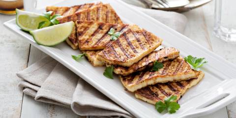 grilled tofu on a plate with limes and cilantro