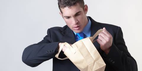 A guy looking in his brown bag lunch at the office