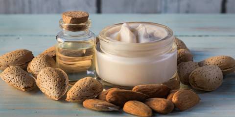 Hand cream and almond oil surrounded by natural almonds