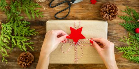 tying a string bow on a gift wrapped in craft paper.