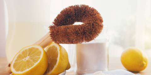 Eco-friendly natural cleaning products, bamboo brush, lemon, baking soda sodium bicarbonate on wooden table.