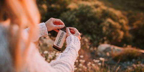 A hiker opening a protein bar