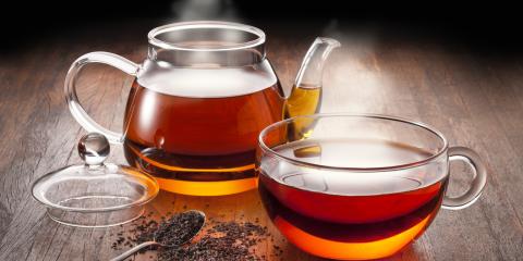 Steaming glass teapot and teacup filled with tea. 