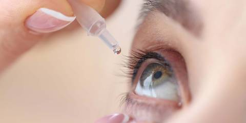 a woman using an eye-dropper of artificial tears