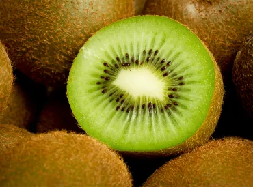 a sliced kiwi surrounded by whole kiwifruit