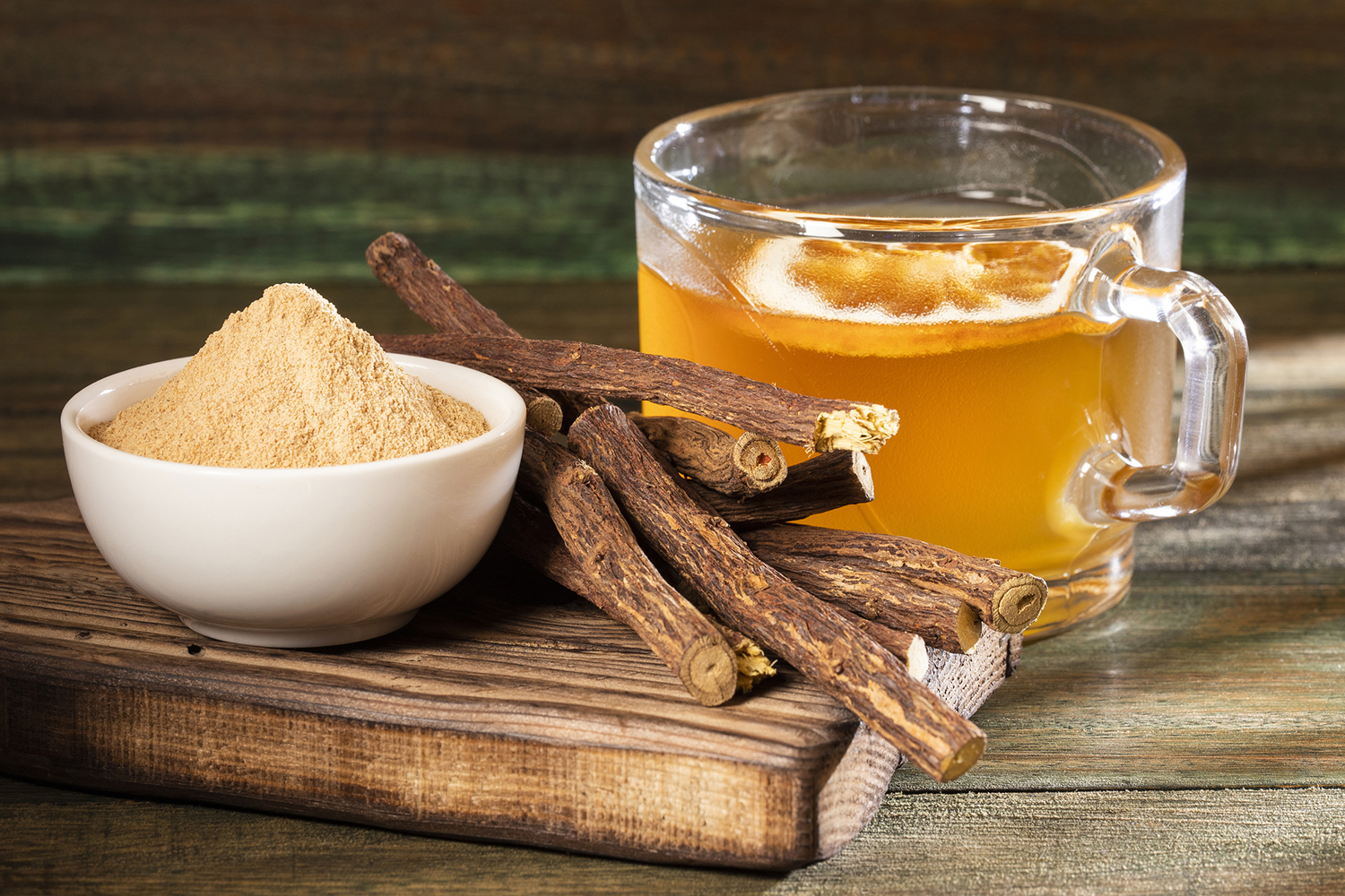 a bowl of licorice powder, dried licorice root, and a mug of licorice tea