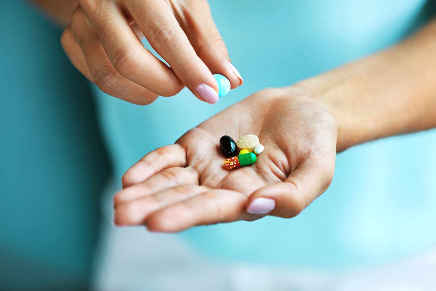 a woman with a few colorful vitamin capsules in her hand