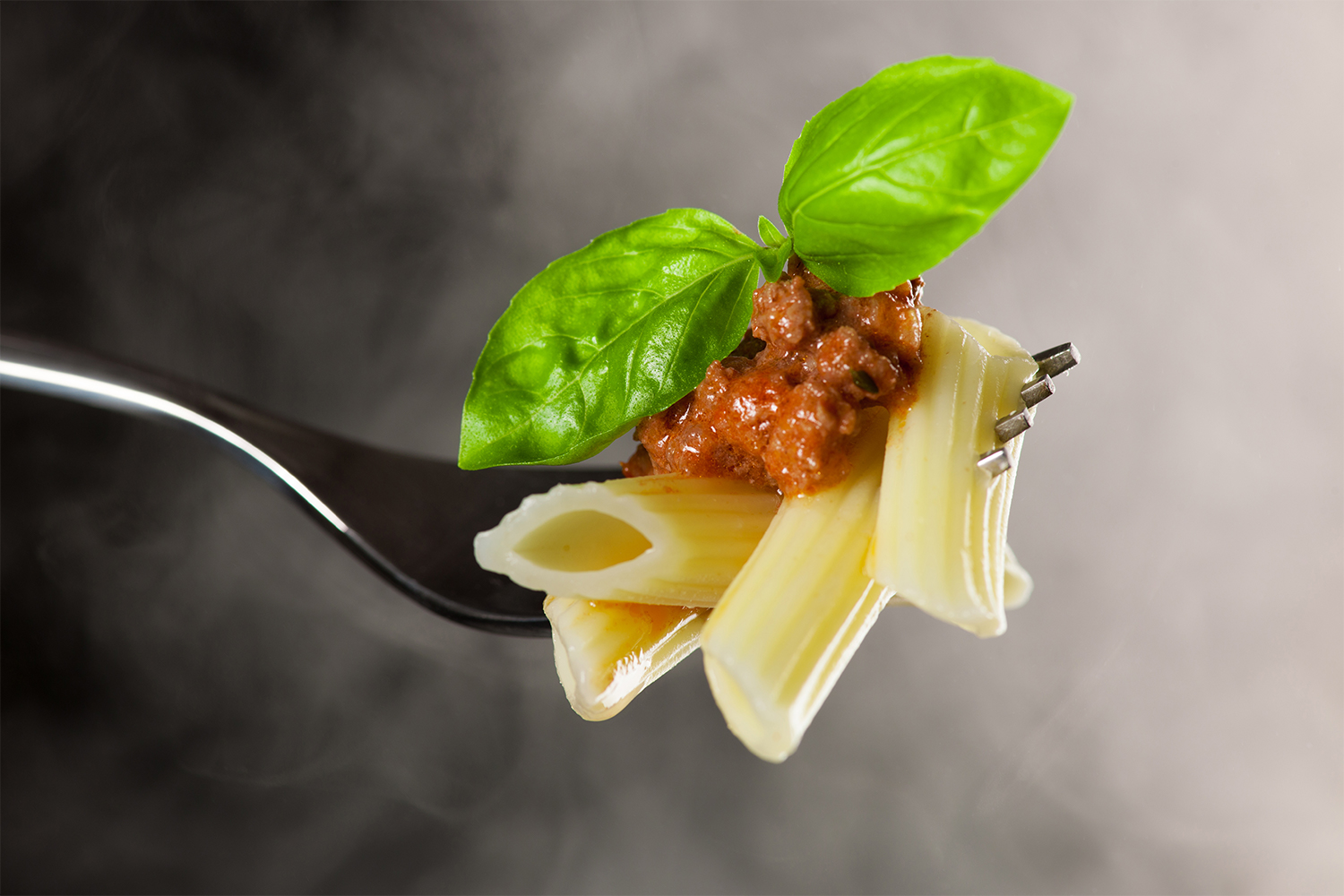 Perfectly cooked penne on a fork with rolling steam